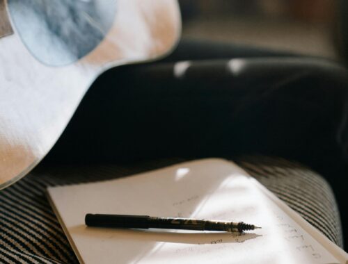 Close-up of an acoustic guitar and notebook, capturing a calm songwriting moment.
